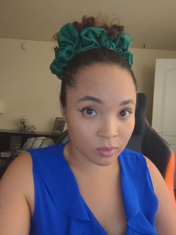 Me in a blue blouse and my hair in a bun tied with a massive green scrunchie