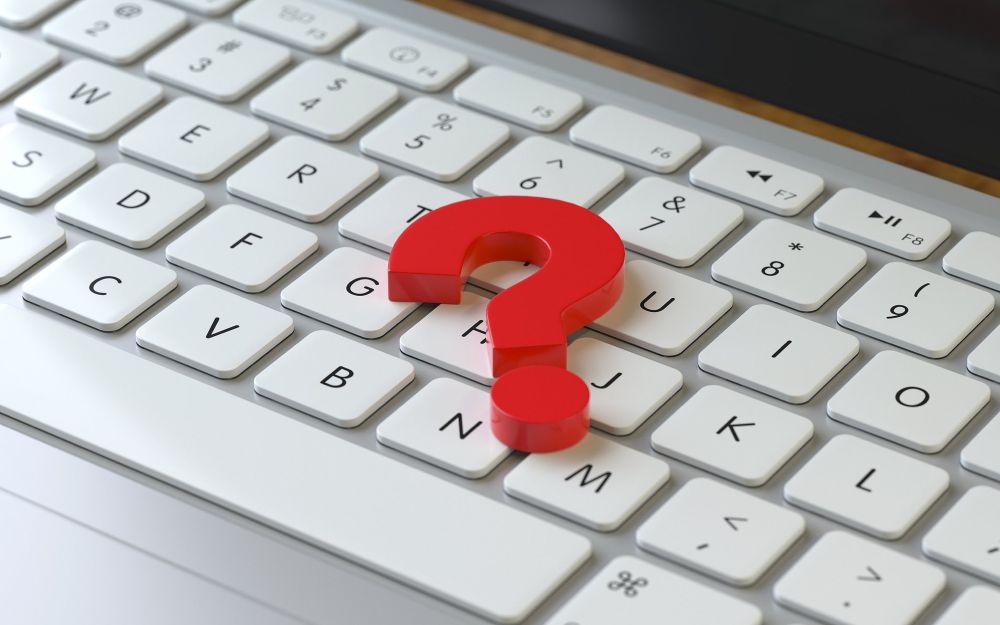 a red question mark magnet sits atop an Apple computer keyboard