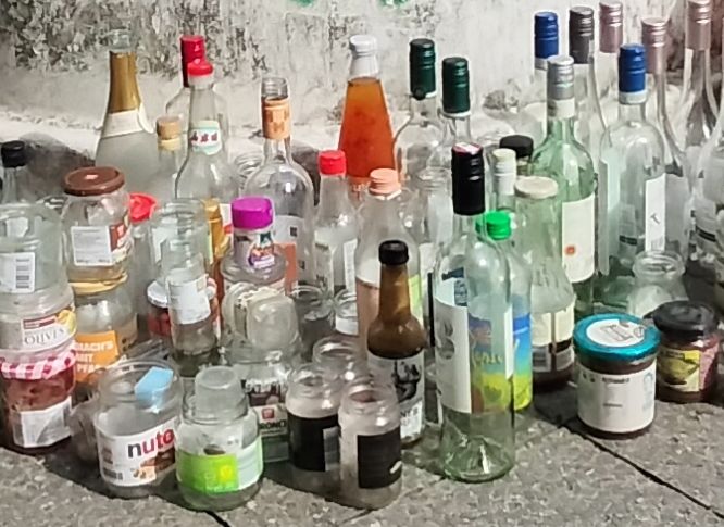 leere flaschen stehen um einen müllcontainer