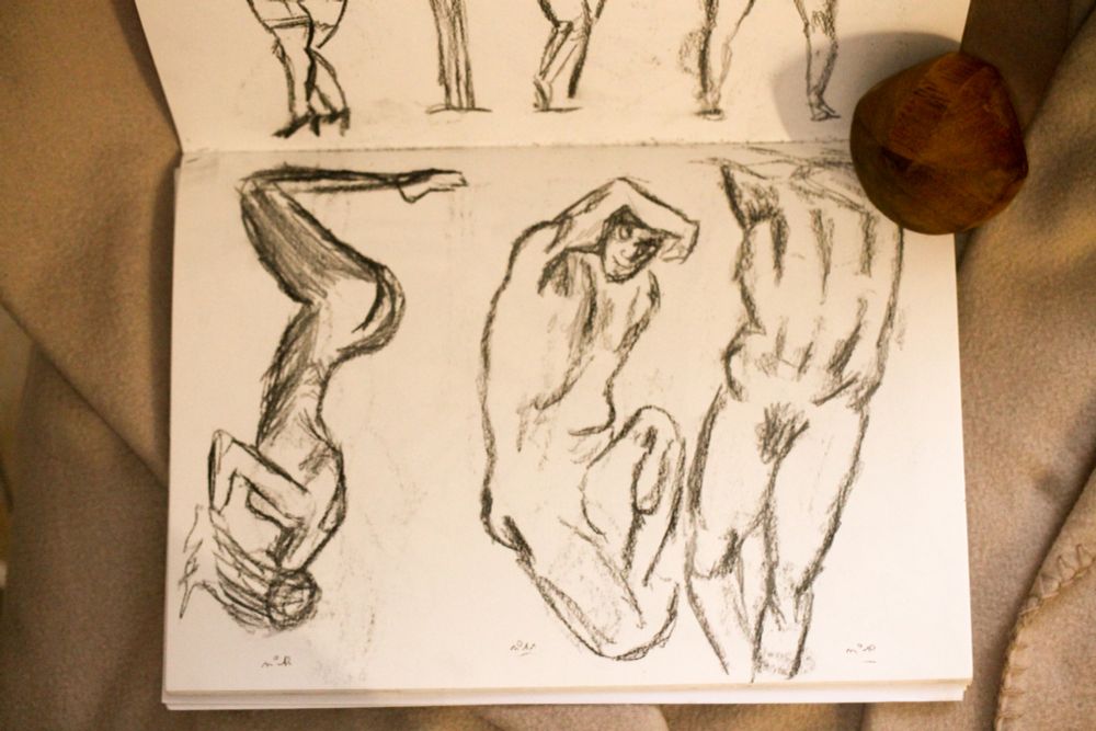 Sketchbook page . It contains three quick charcoal pencil sketches of artistic nudes. 2 men 1 woman standing in different attitudes 