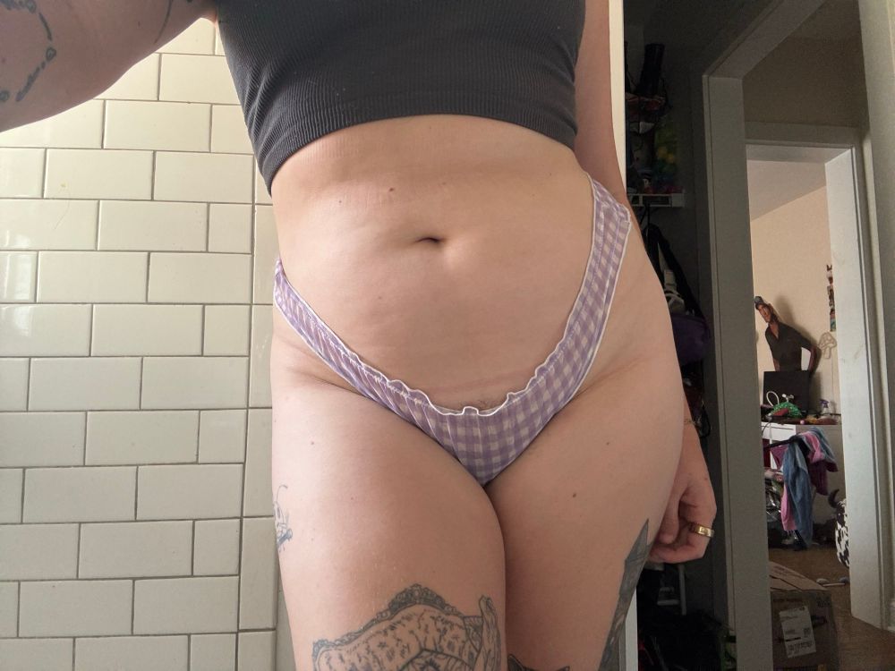 selfie photo of my hips and thighs, crossed in front of one another. i wear little purple and white checkered underwear and a grey tank top 