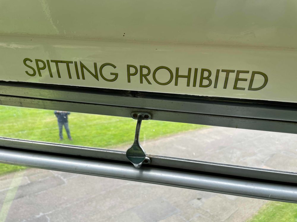 A sign in a bus that says spitting prohibited