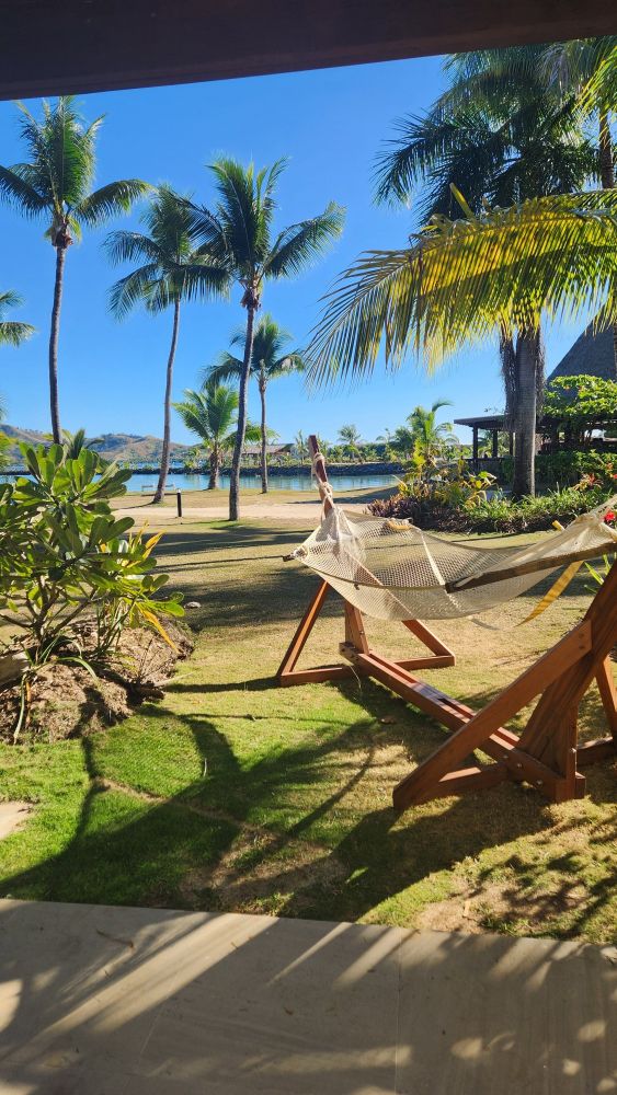 Image taken from a Fiji resort hotel room door shows an idyllic scene consisting of a hammock, palm trees, and an inlet at high tide