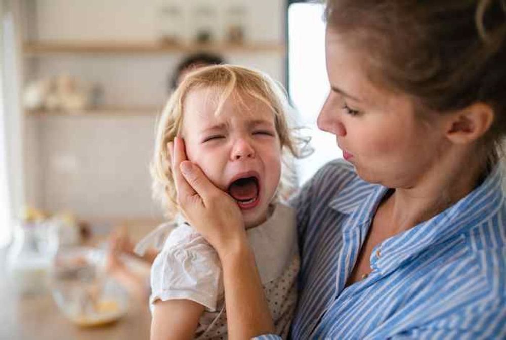 Une fillette pleure dans les bras de sa maman.