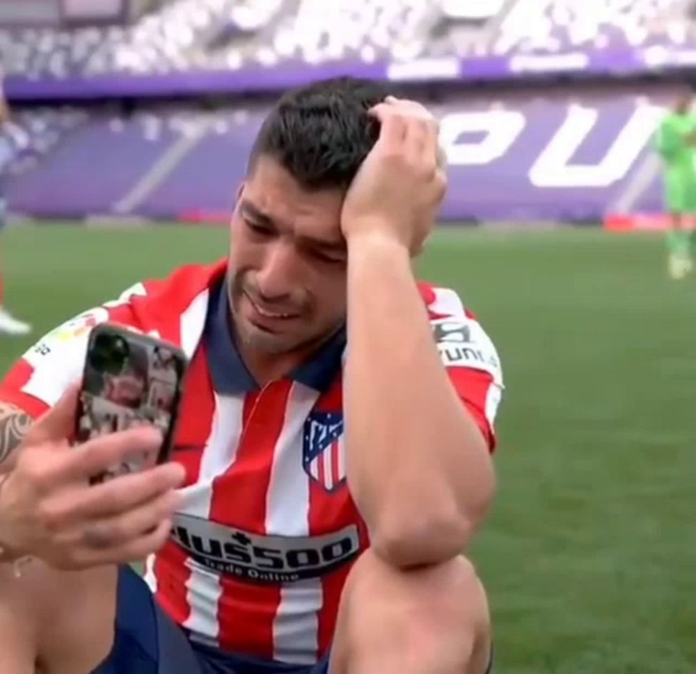 a man in a red and white striped shirt is taking a picture of himself on a cell phone .