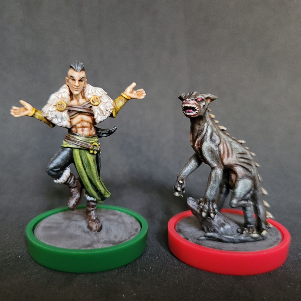Painted miniatures for Loki and Chupacabra from Unmatched Battle of Legends volume 3. Loki is bare chested with white fur capelet over his shoulders, green sash on his hips, black leather pants, boots with the fur, and golden accessories. Chupacabra is an elongated deathly looking dog creature with teeth revealed in unnatural circle formation, black lean body with spikes on its back.