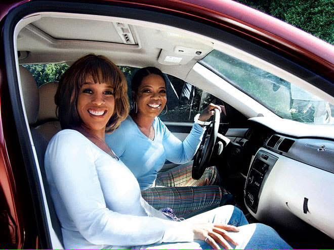 Oprah and Gayle smiling while sitting in the front seat of a car