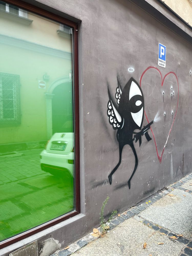 Pan Peryskop on a wall with a machine gun and some wings. He shoots into a big heart. 