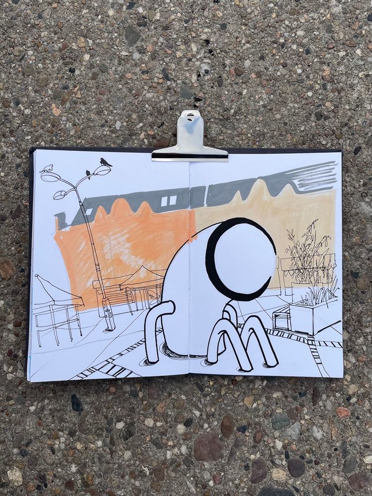 There is a sketchbook on a footpath. The drawing shows the market square and the Pan Peryskop sculpture in Poznań.