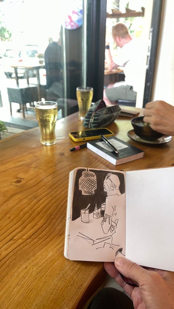The sketch on location, my tiny sketchbook in my hand, outside the man sitting at the table. 