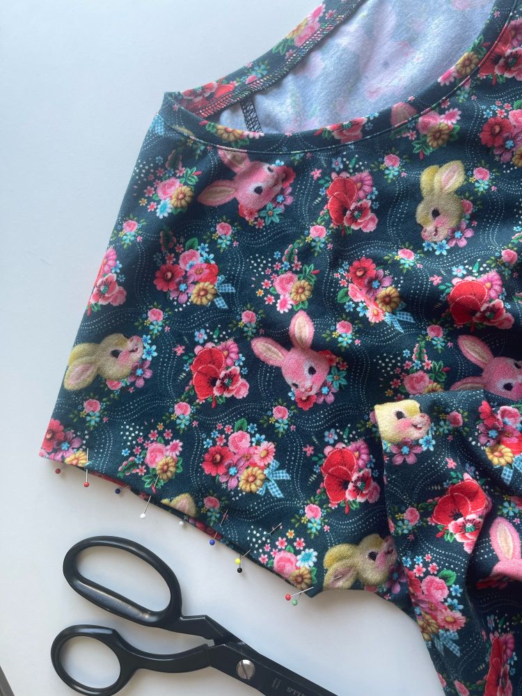 There’s a t-shirt with a bunny & flowers pattern. The arm seam is prepped with needles, bc it’s not finished.