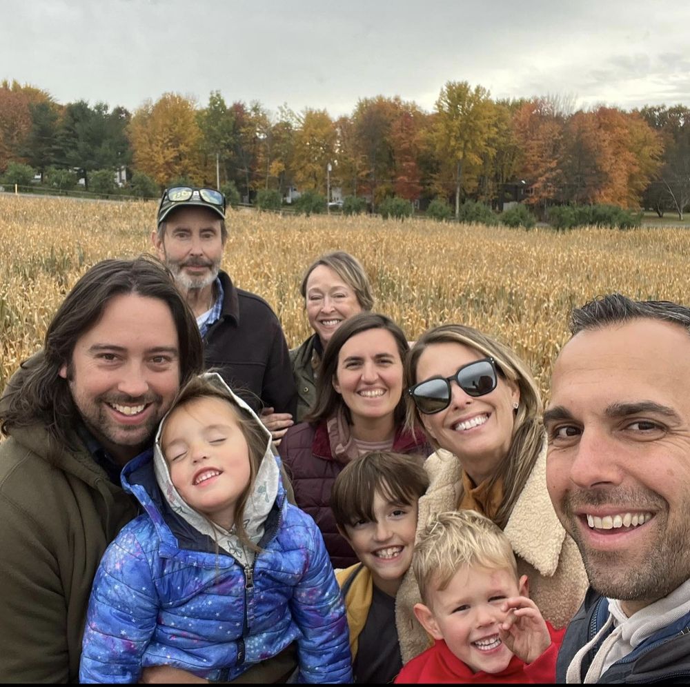 People standing, smiling, on a wooden bridge in the middle of a cornfield.