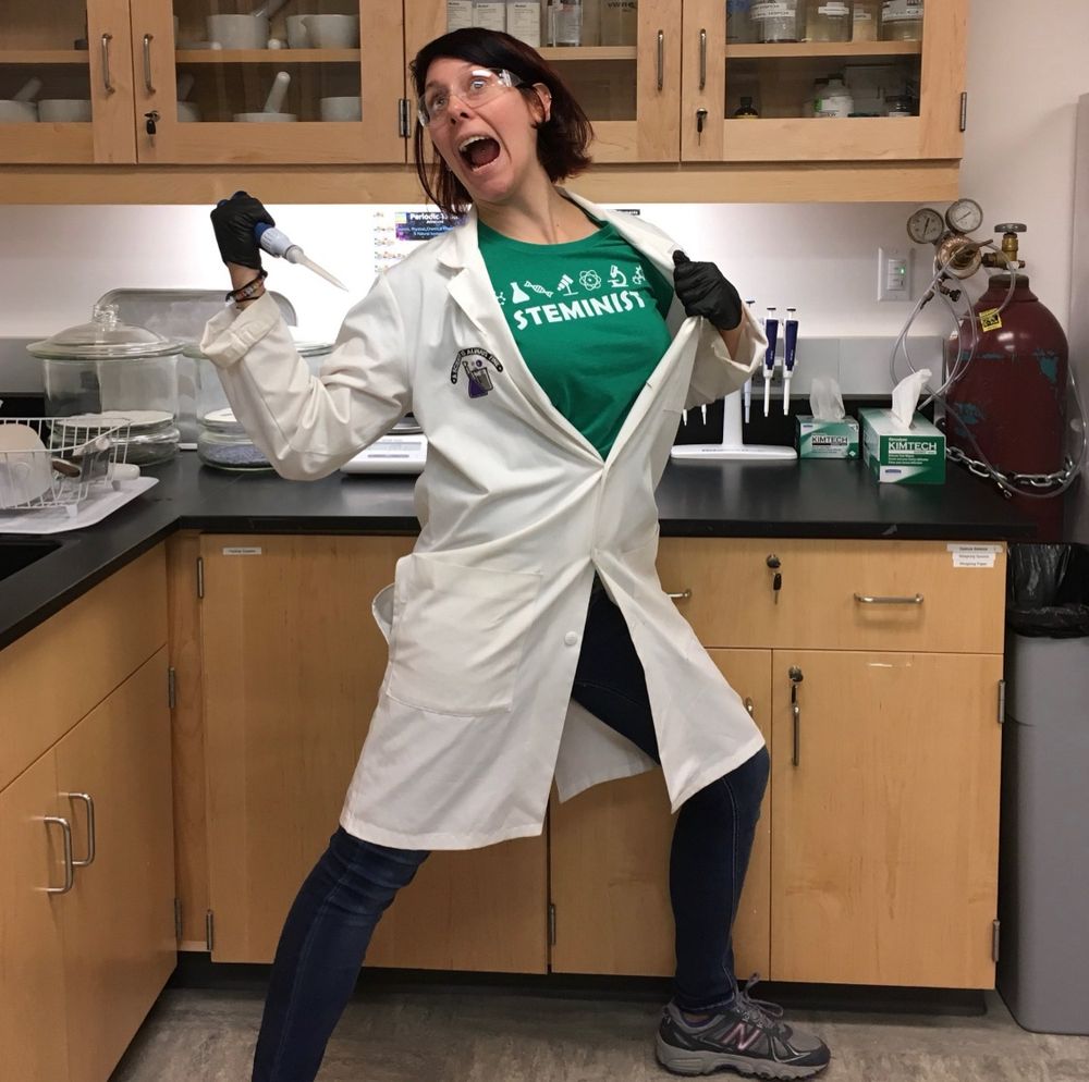 A photo of me posing in a silly way in a laboratory setting with proper PPE and a pippette.
