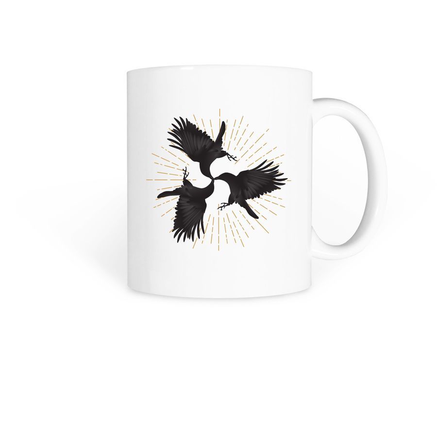 A white coffee mug with three flying black ravens that meet at the beaks in a design that hints at Celtic animal designs. There's a starburst of golden energy behind the ravens. 