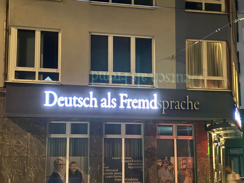 Sign advertising German classes for foreigners (Deutsch als Fremdprache) but the word Sprache is not lit up, leaving Deutsch als Fremd