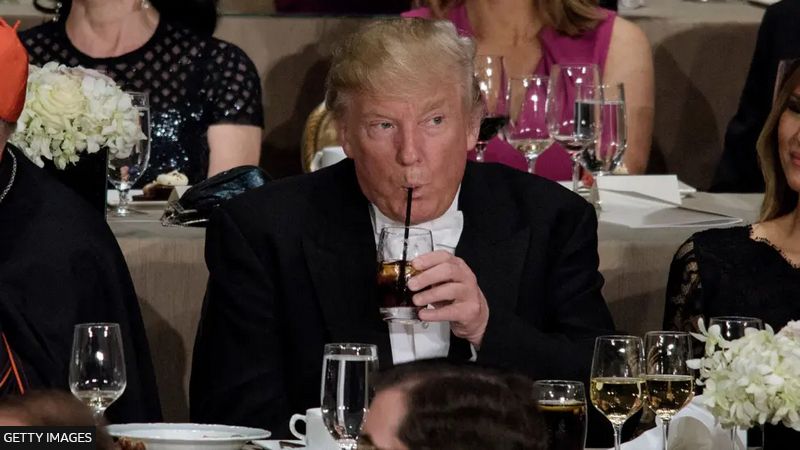 trump drinking out of a straw at a dinner