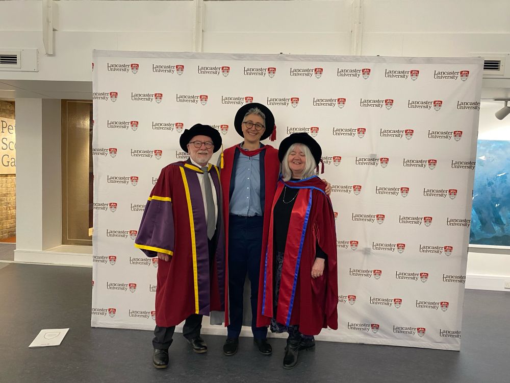 Three happy people in academic regalia