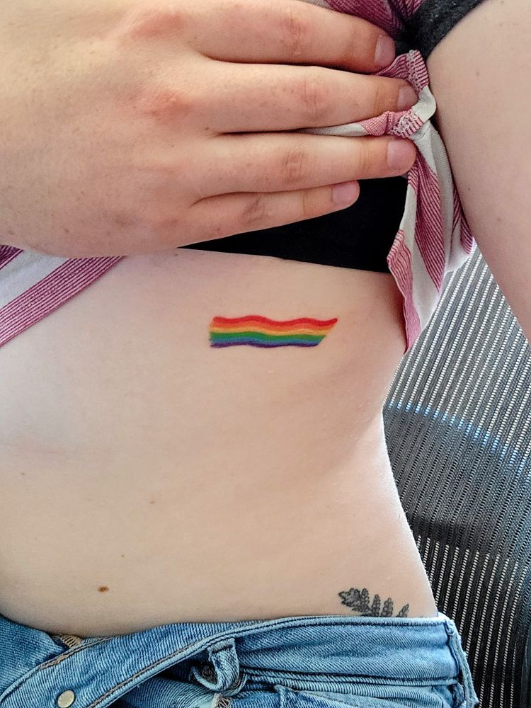 photo of a small rib tattoo depicting a wavy rainbow flag