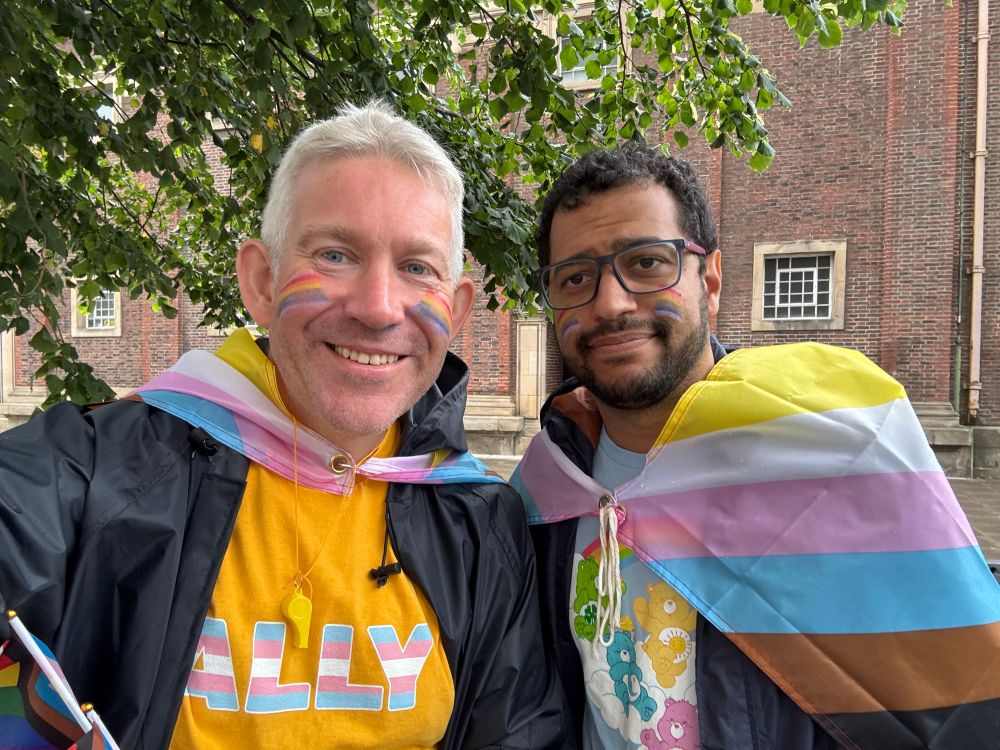 Matthew and Lucas looking at camera, wearing progress pride flags 