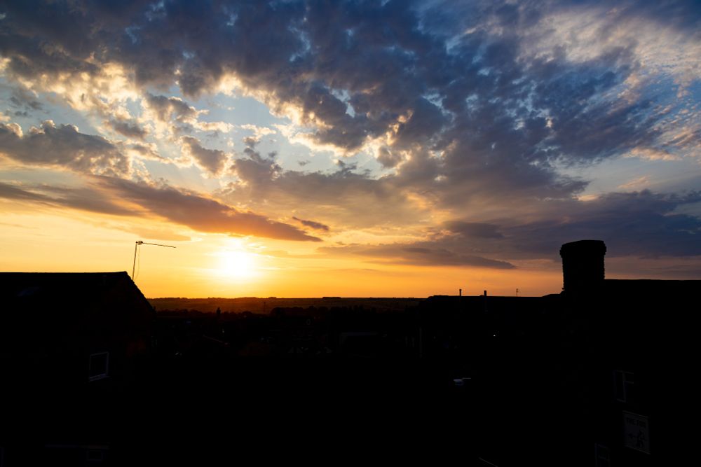 Sunset over a town skyline/horizon with dramatic contrasting blue and amber skies