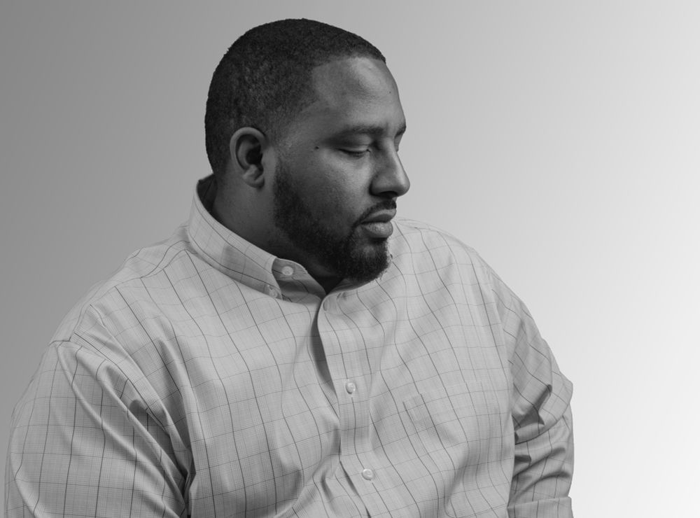 black and white photograph of a man for his portfolio. He is looking downward. 