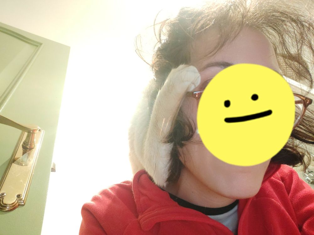 my cat's paw gripping my face while he sleeps on my back