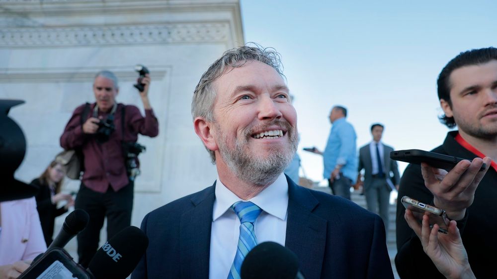 Thomas Massie smiling surrounded by reporters