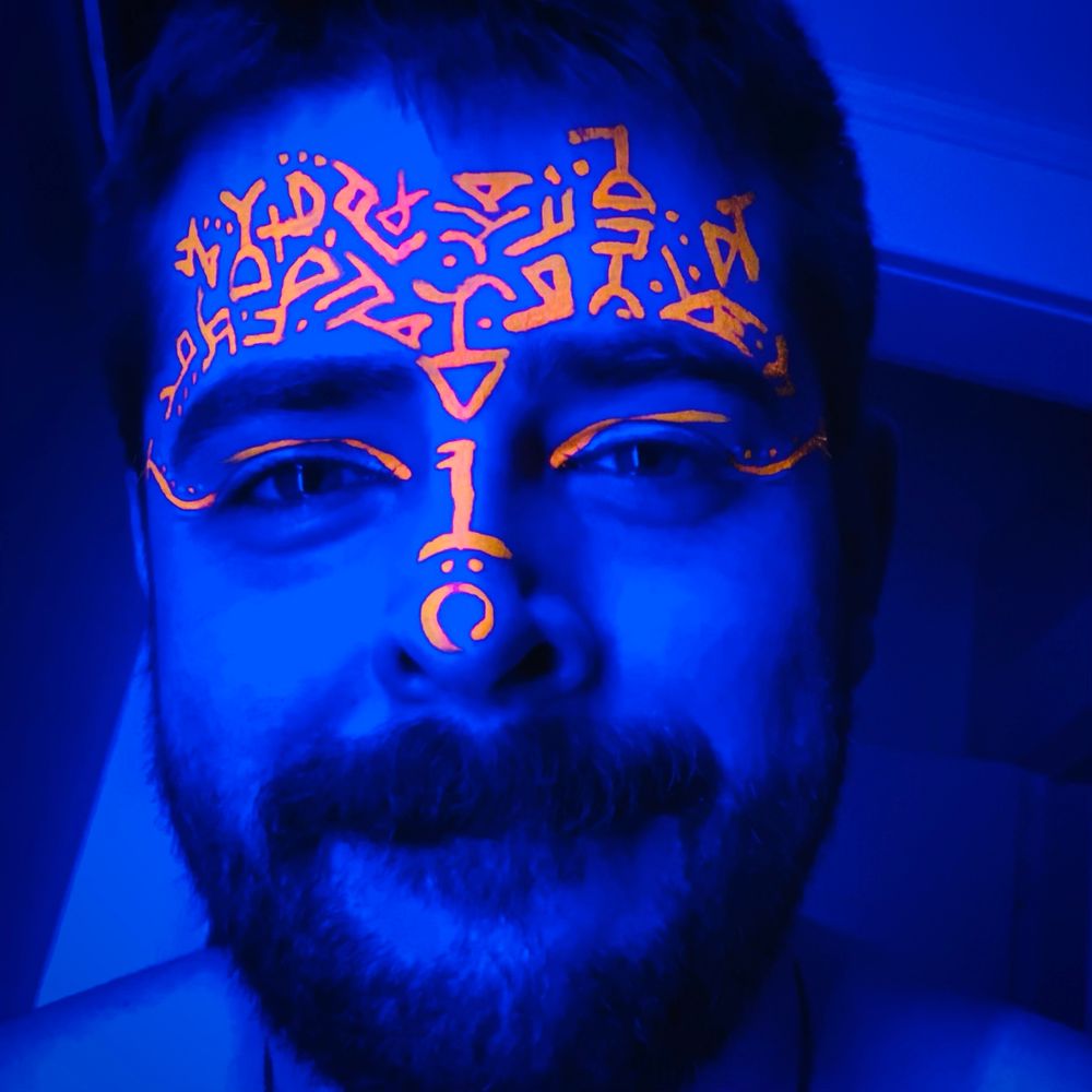 A selfie of me cast in blue light with orange symbols I custom painted on myself