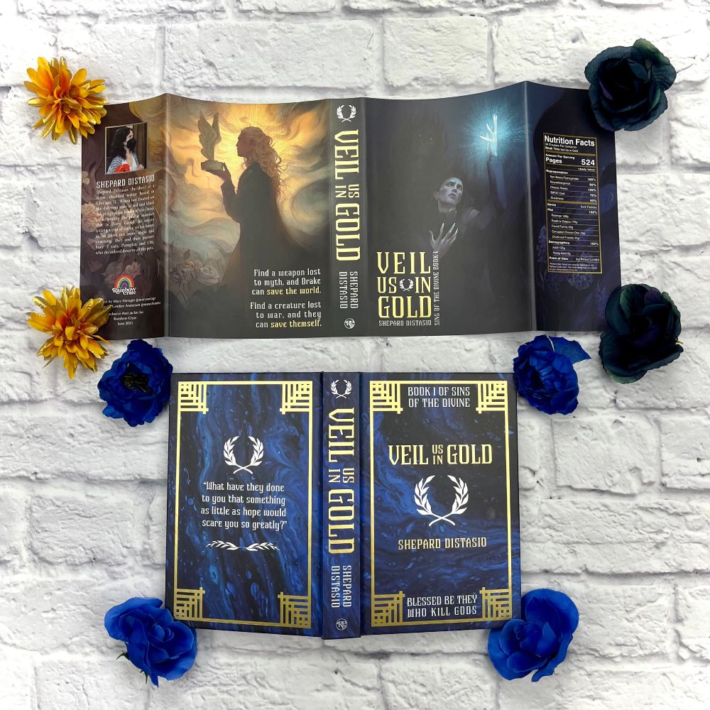 The dust jacket laid out above the full naked hard case. Dark teal flowers sit at the right corners, while gold flowers sit at the left corners of the dust jacket. Deep blue flowers sit at each corner of the hardcase. Everything lies on a white brick background.