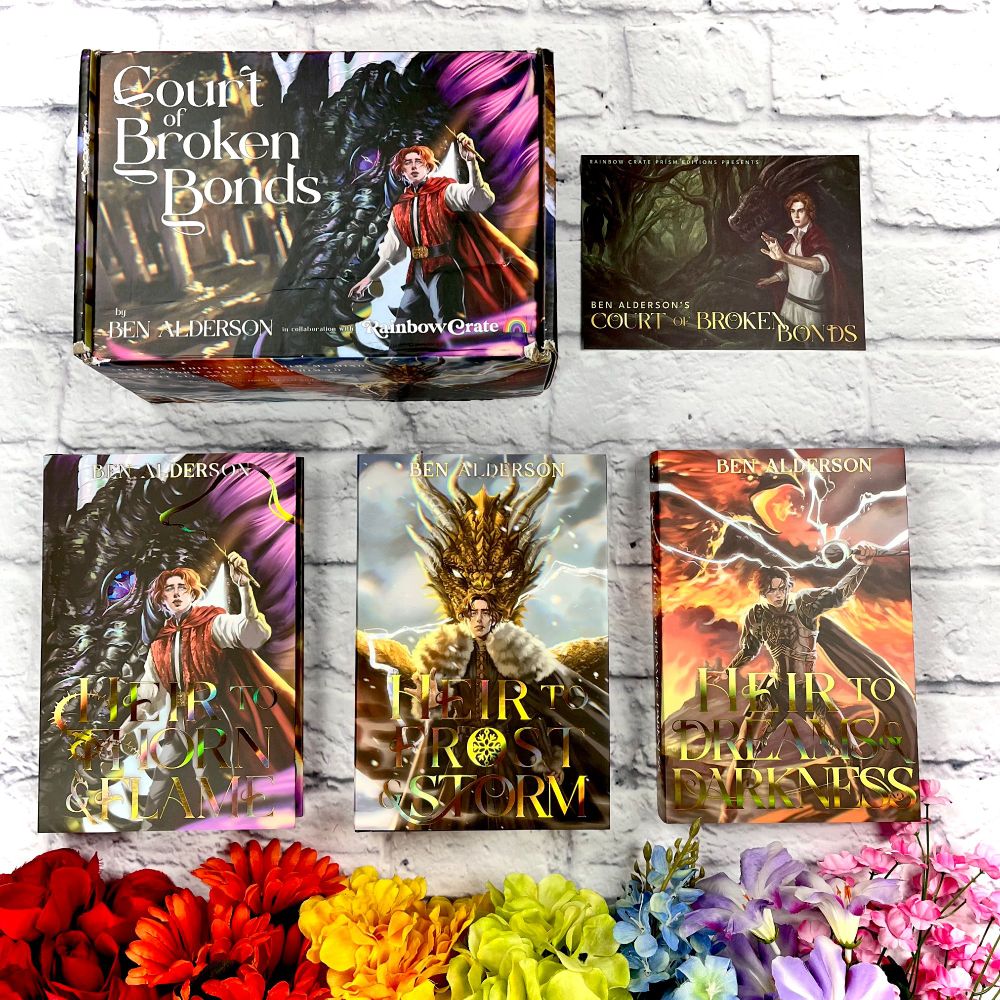 A photo of the Court of Broken Bonds series by Ben Alderson. At the top of the photo is the custom shipping box next to the spoiler card. The three books lay underneath these, in order: Heir to Thorn & Flame, Heir to Frost & Storm, and Heir to Dreams & Darkness. Below the books are rainbow flowers. Everything sits on a white brick background. 