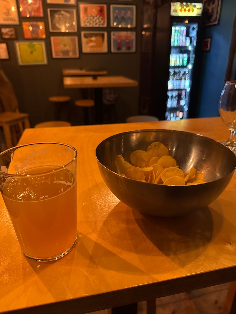 Unfinished glass of an IPA with a big bowl of crisps