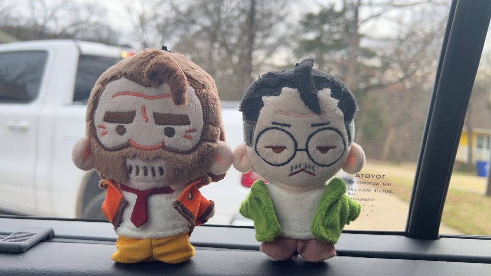 plushie harry du bois and kim kitsuragi sitting side by side, jackets swapped