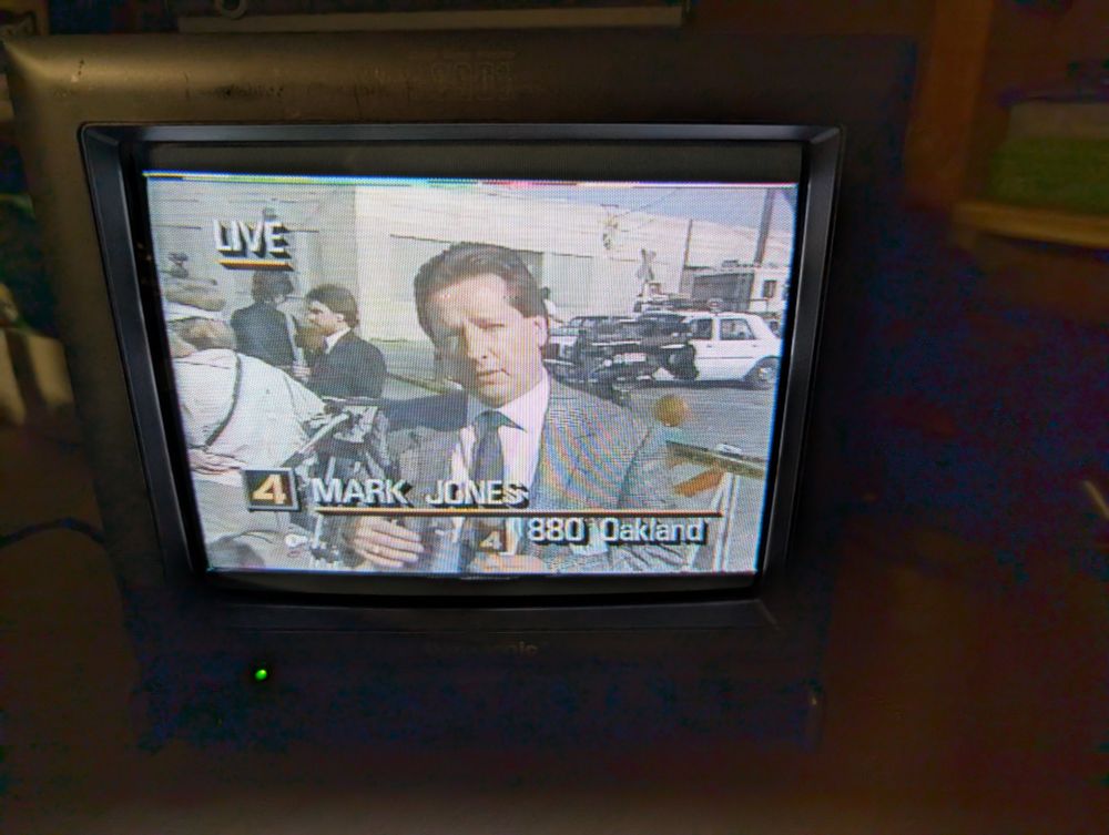 Photo of a CRT TV showing a news broadcast. It's Mark Jones from KRON4 live from 880 Oakland