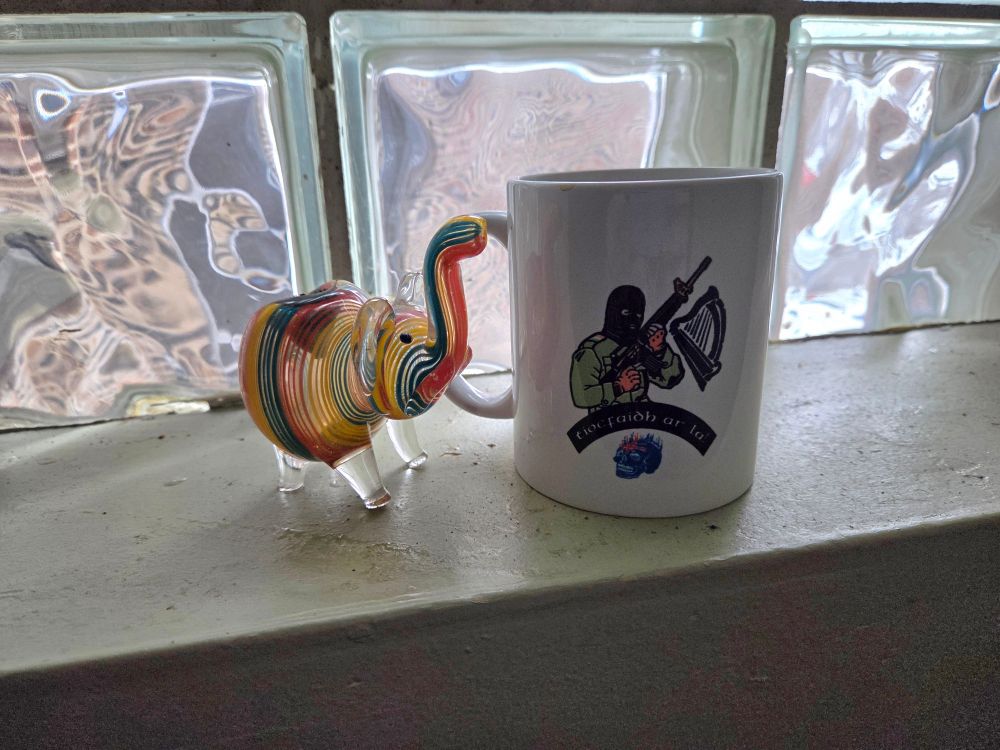 a smoking device shaped like an elephant next to a coffee mug featuring an IRA soldier with the text "Tiocfaidh ár lá"