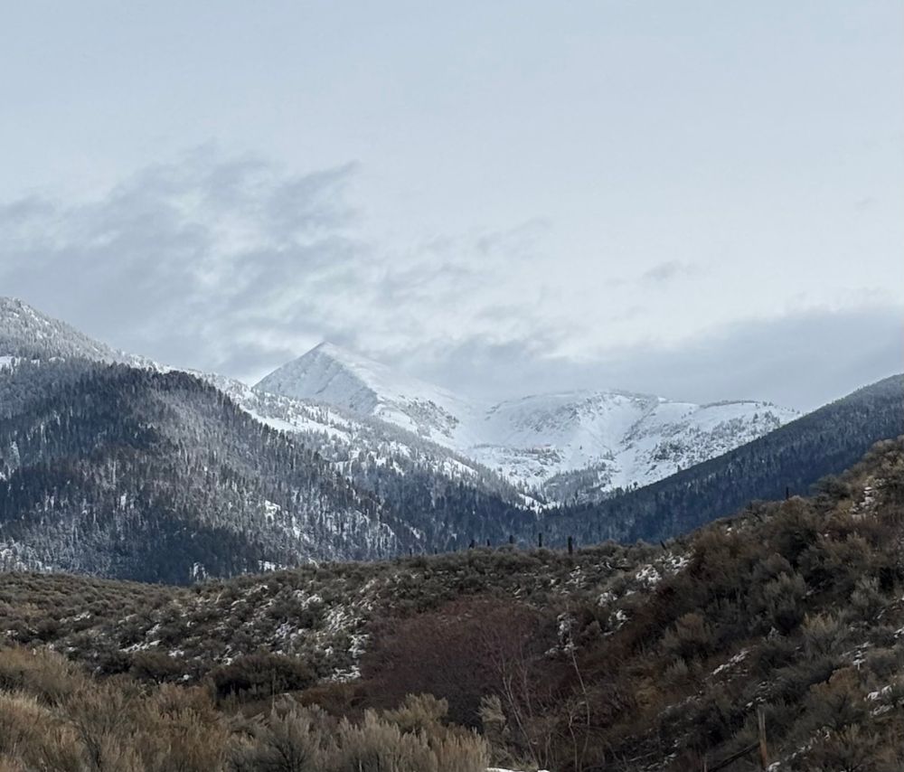 Snow covered mountain with clouds and a bit of blue sky 