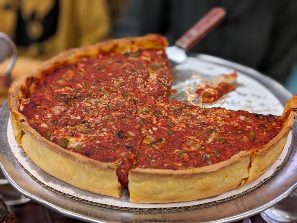A thick deep dish pizza with 2 pieces removed