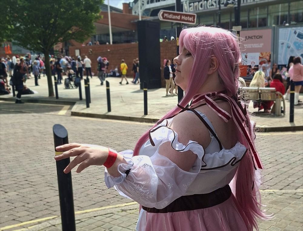 a photo of my nikki cosplay. waist-up, turned away from the camera with eyes closed, gesturing with one hand.