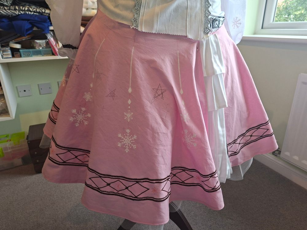 a pink skirt with painted snowflakes and a dark brown trim embroidered on
