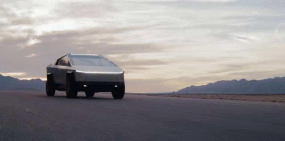 a tesla cybertruck is driving down a road in the desert