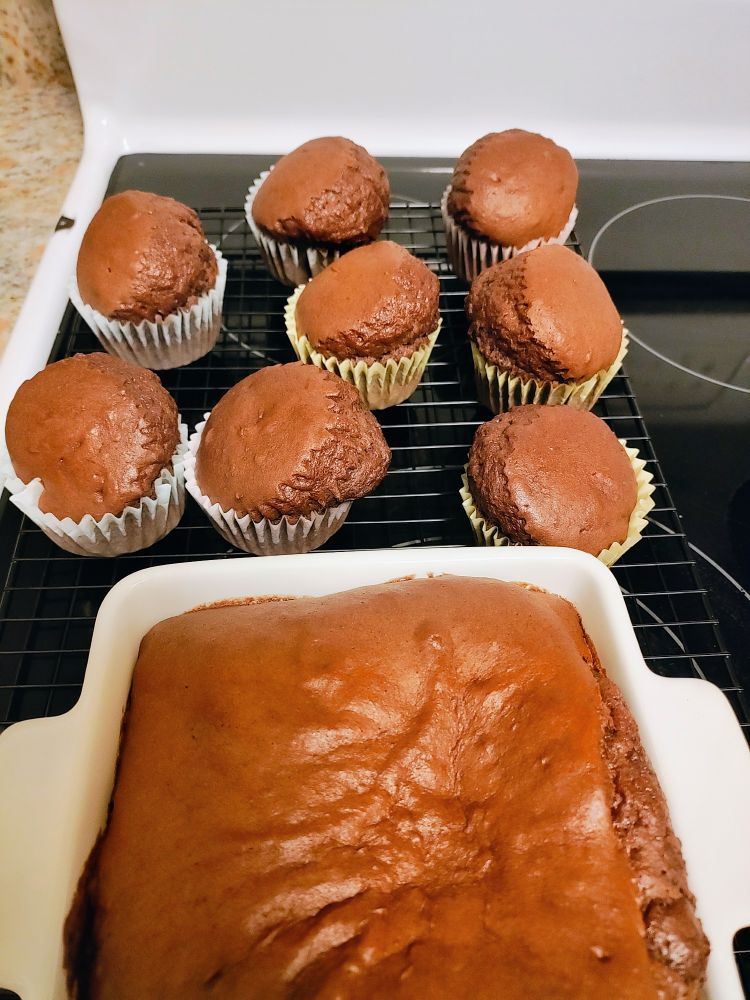 8 chocolate cupcakes and one small square baking dish with muffin tops