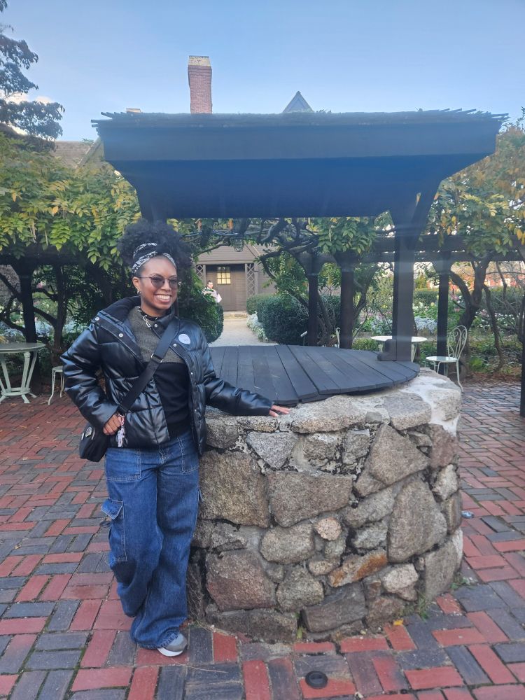 Me, a black woman, standing by a stone well within the city area of the House of the Seven Gables in Salem, MA