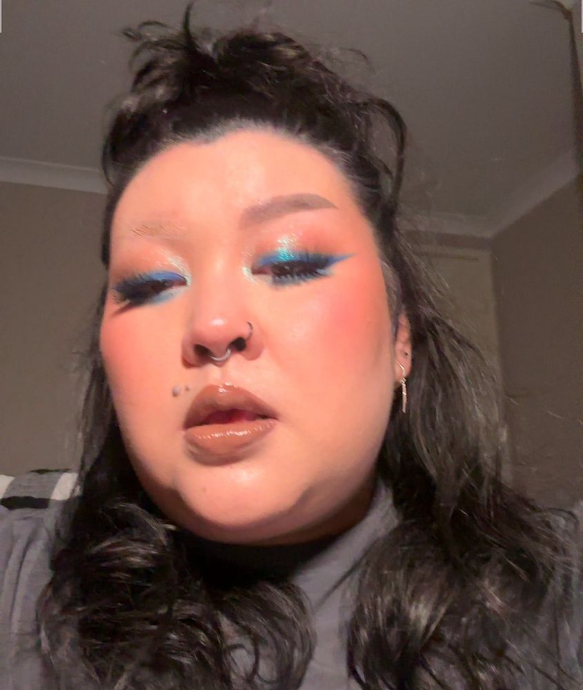 A selfie of Clore with blue winged liner.  They are looking down into the camera. 