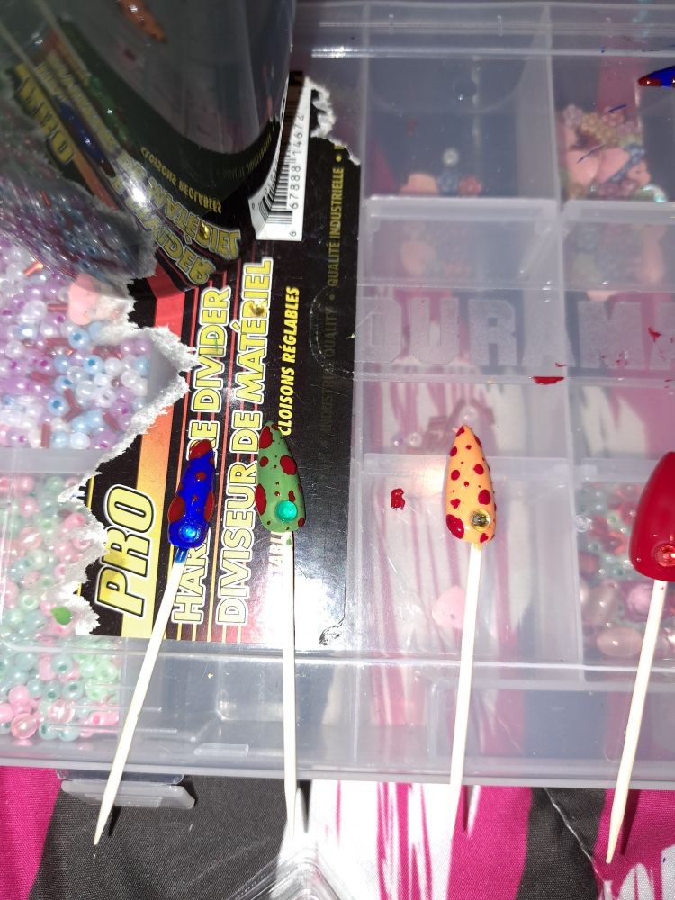 Three fake long nails, blue, green and orange with fake blood splatters on them