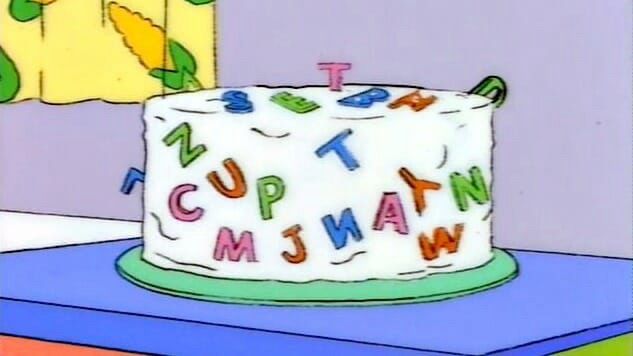 Screenshot from the Simpsons of a white iced cake with random letters all over 