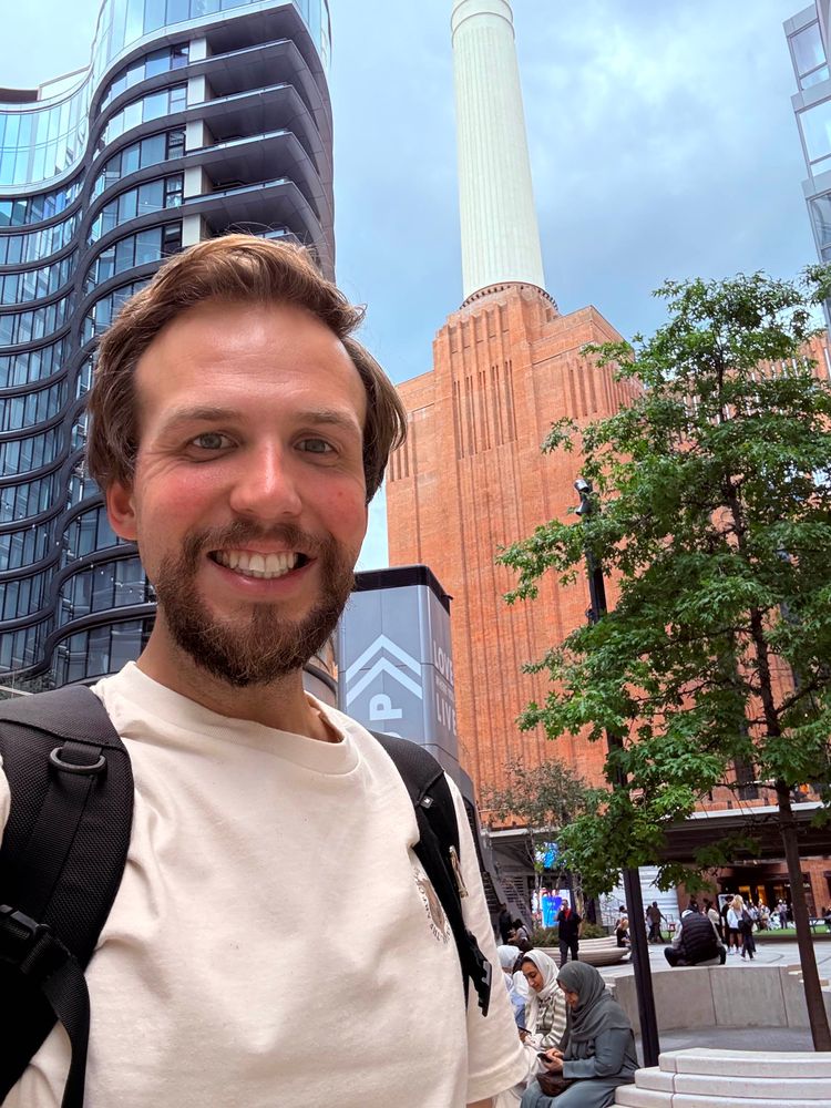 Smiling Klemens with a backpack standing in front of Battersea power station.