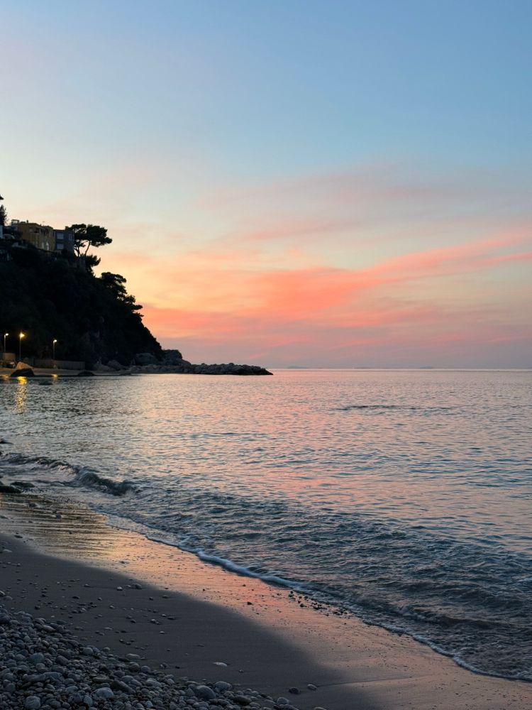 Beach at sunset, with pink and yellow clouds above