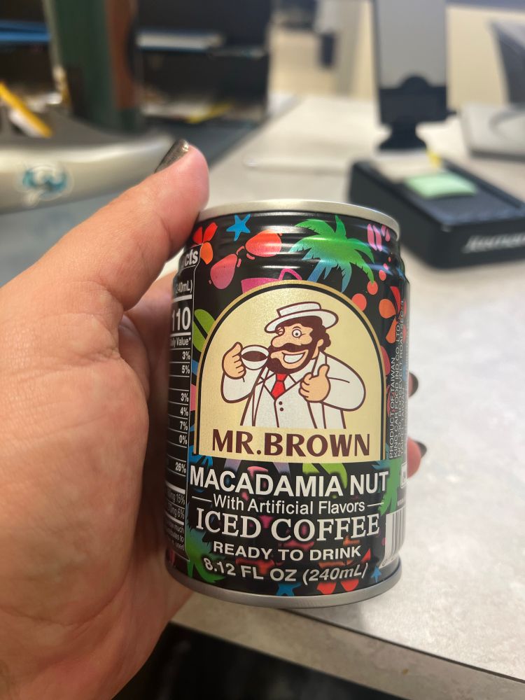 my hand holding a can of mr brown’s macadamia nut coffee
