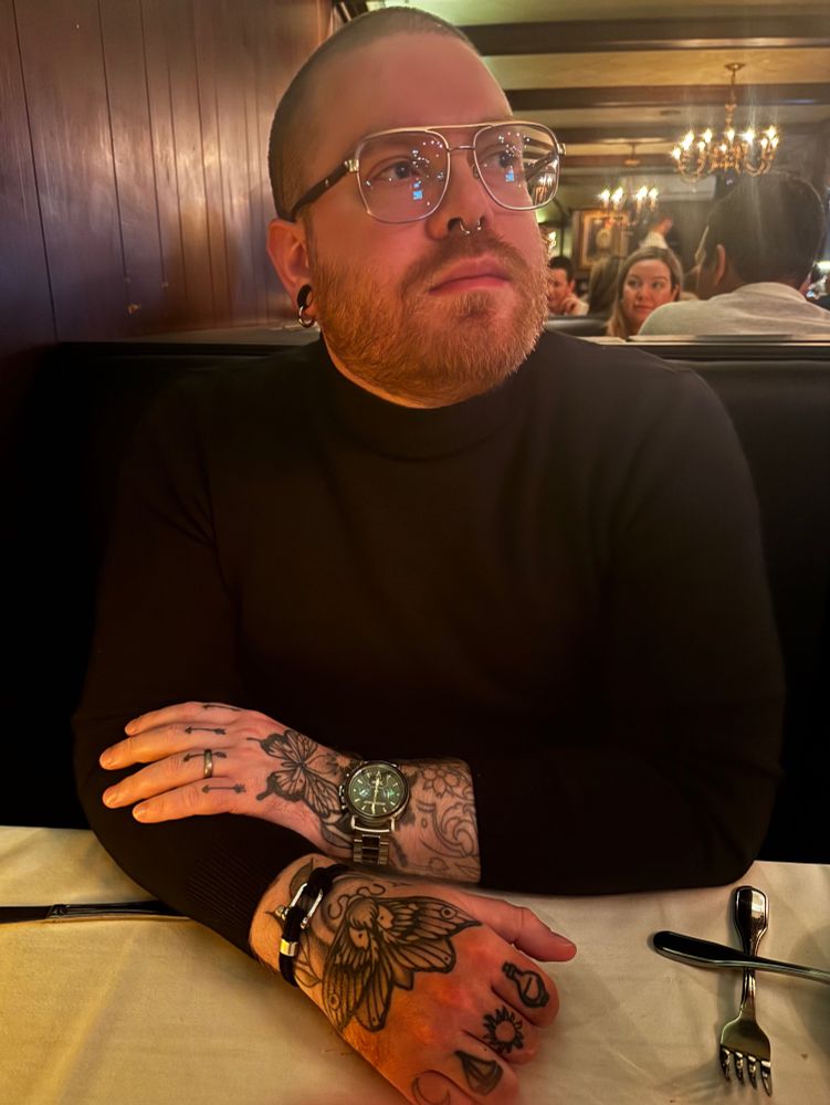 my husband wearing a black turtleneck and a fancy watch centered in the frame staring off into the distance at a nice Italian restaurant