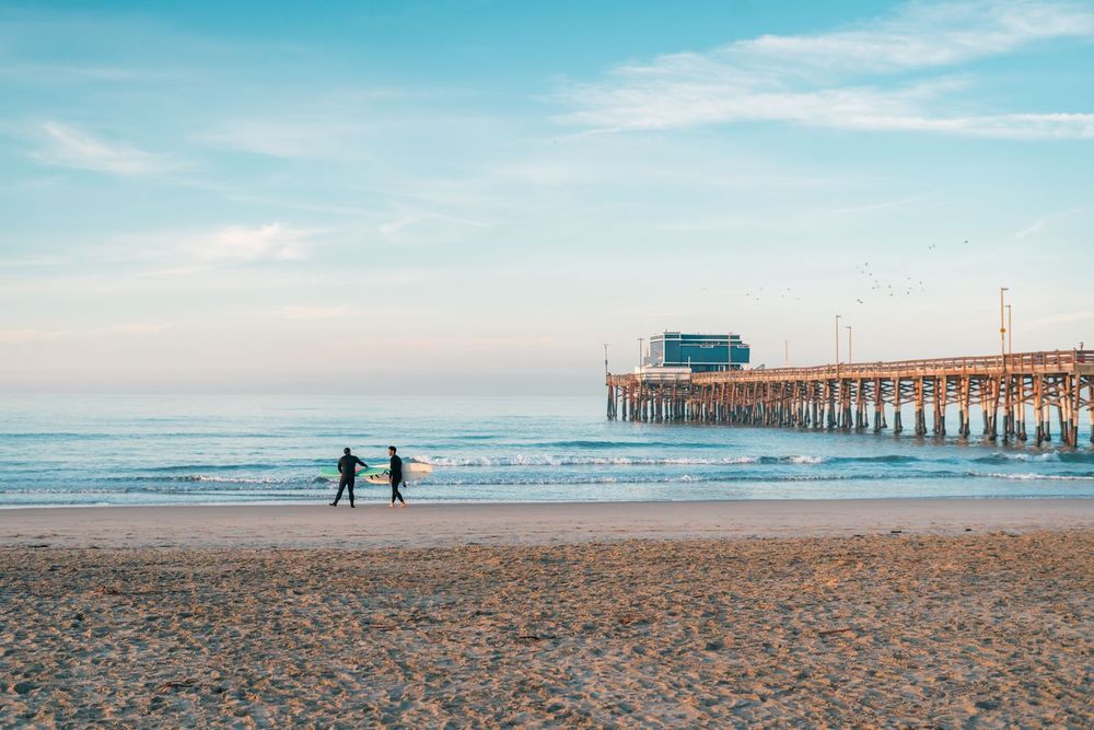Surfers enter the water in front of Newport Beach Pier