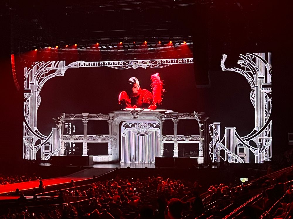Lady Gaga’s stage which looks like an opera house, where she sits atop it in red velvet writing a manifesto with a red plume quill